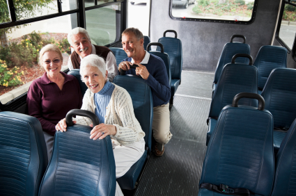 Two senior couples on a trip, riding a shuttle bus. Focus on woman with white hair.